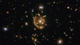Слика од вселенскиот телескоп Хабл на објектот познат како галаксијата Стопен прстен, GAL-CLUS-022058s, PKS 0218-387. Околу објектот јасно забележлив е Ајнштајнов прстен.